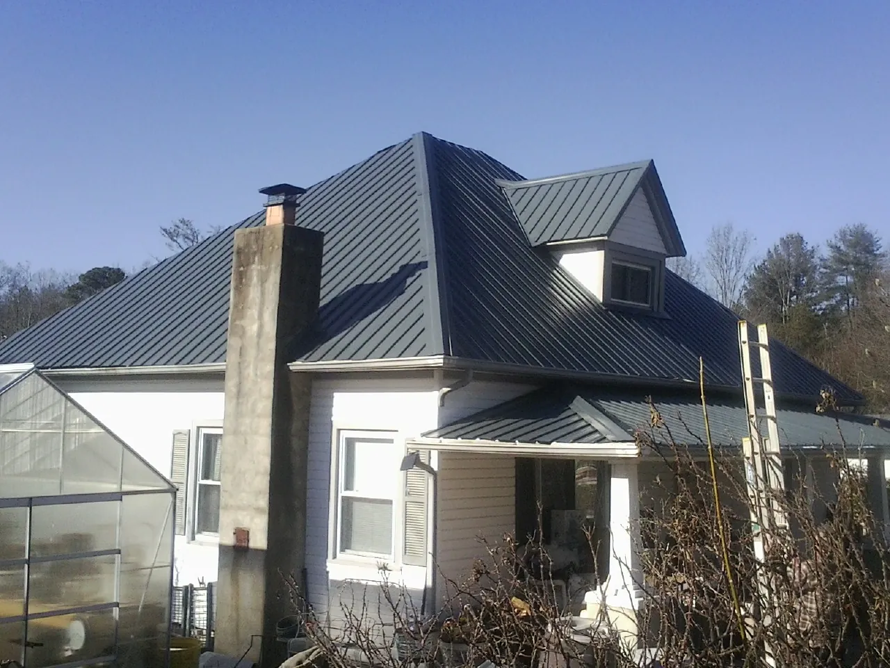 Dark blue standing seam metal roof on a white farmhouse with dormer — Slate & Tile Roof Repair by Roofing Brothers in Piqua