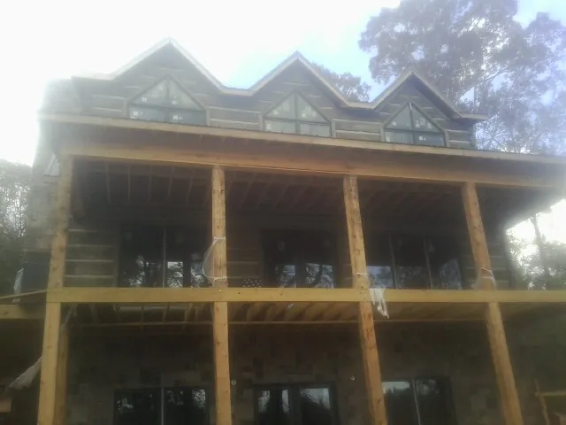 Dormers and porch framing on a large log home under construction — Roof Coating work by our crew in Piqua