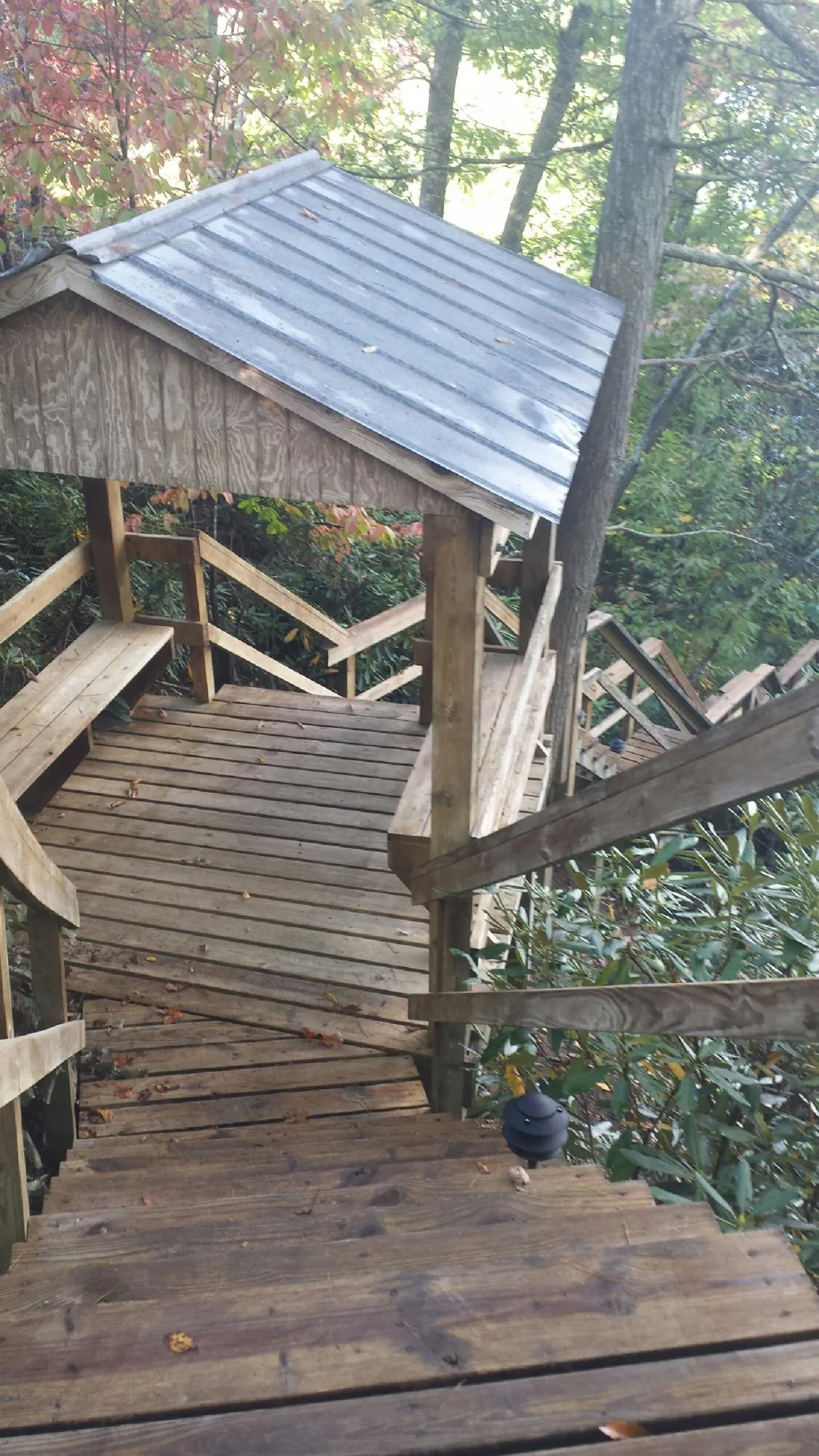 Metal roofed shelter over wooden steps on a wooded walkway — Skylight Repair & Installation work by our crew in Piqua