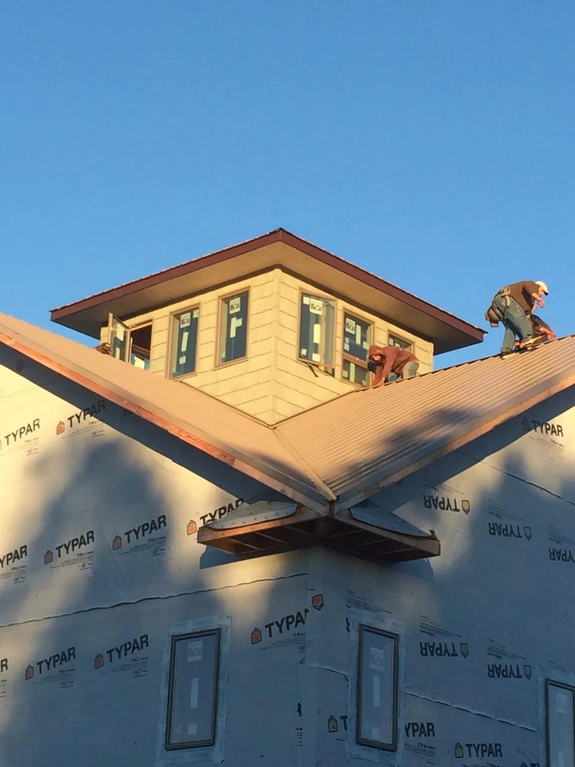 Roofers working around a rooftop cupola on a new metal roof at sunset — Roof Waterproofing in Piqua by Roofing Brothers